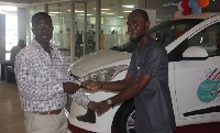 West Hills Centre Manager, Mr. Quarmson presents keys to the brother of the winner, Mr. Yawson.