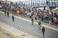 Spanish police officers and soldiers escort a large group of migrants to the border