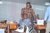 A beneficiary [seated] with a broad smile