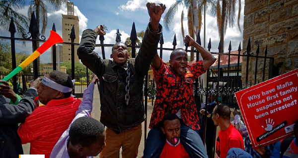 Protesters briefly climb the gates of Parliament, one holding a placard referring