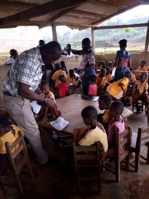 Nzema East MCE Frank Okpenyen distributing the shoes to the pupils