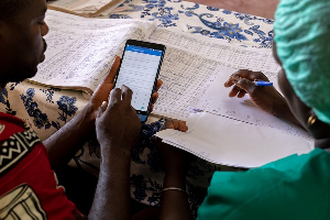 Sampson Dzivor (left) taking a woman through data entry