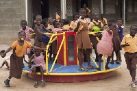 Children play on the merry-go-round outside their school, that generates electricity.