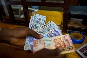 A man trades U.S. dollars for Ghanaian cedis at a currency exchange office in Accra, Ghana, June 15,