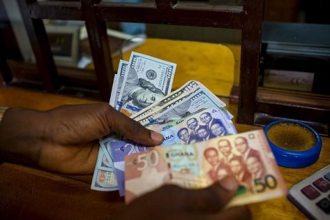 A man trades U.S. dollars for Ghanaian cedis at a currency exchange office in Accra, Ghana, June 15,
