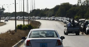 Libyan men walk past a long queue of cars waiting for fuel in Tripoli