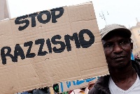 A migrant holds a placard reading 'stop racism' during a demonstration in Rome on June 16, 2015