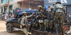 M23 rebels gather on a pick-up truck with recovered guns during a community street-cleaning exercise