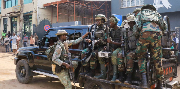 M23 rebels gather on a pick-up truck with recovered guns during a community street-cleaning exercise