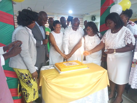 Dr Owusu (4th left) being supported by some management members to cut the anniversary cake