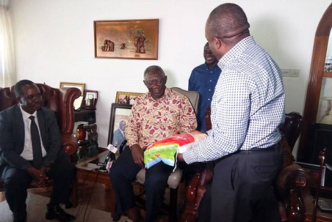 Julius Wambura (L) a member of ARAP presents bag of local rice to former president Kufuor