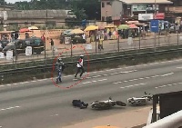 A police lay in the road after being shot while the suspects run off across