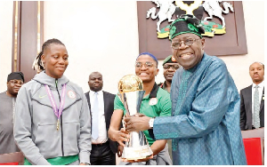 President Tinubu (left) beaming with smiles while receiving the WAFCON trophy