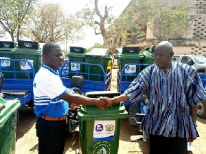 Mr John Sackey (left) handing over waste bins and motorized tricycles to Mr Joseph Amiyure