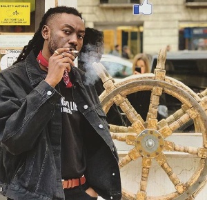 Pappy Kojo puffing a cigarette