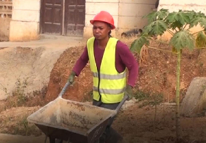 John Quansah pushing a wheelbarrow