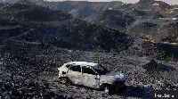 A burnt out car sits among the ashes near Bedar