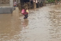 A man carrying two children to prevent them getting carried away by the waist deep waters