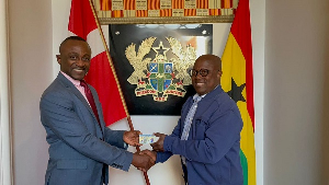 Prof. Ken Attafuah (right) presenting the Ghana Card to a staff at the Ghana Embassy in Denmark