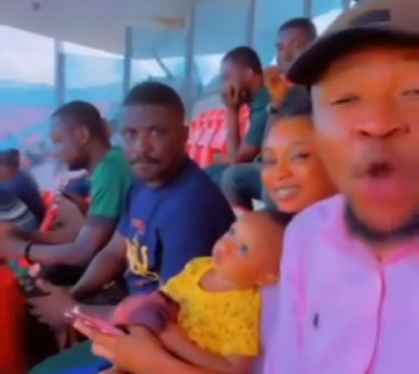 Aweh in a cap with Stephen in blue, watching a Kotoko game together with a lady in the stands