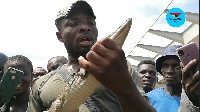 The man displaying the crocodile he is selling to be able to get money to pay school fees