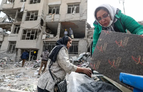 Family members gather their belongings after an air strike on an apartment block in Tehran, Iran