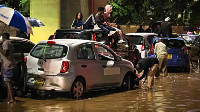 People climb on top of their cars after heavy rains flooded roads in Nairobi, Kenya