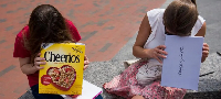 Two girls look through their pinhole boxes during the partial solar eclipse in Boston, USA