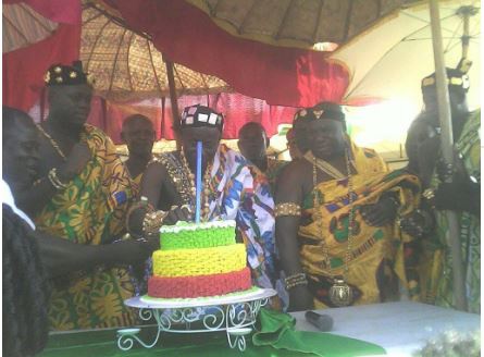 Nana Nuako being helped by other chiefs to cut his anniversary cake