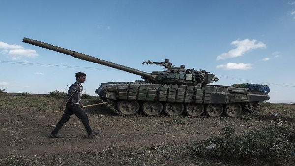 A shepherd walks in front of an abandoned tank belonging to Tigrayan forces