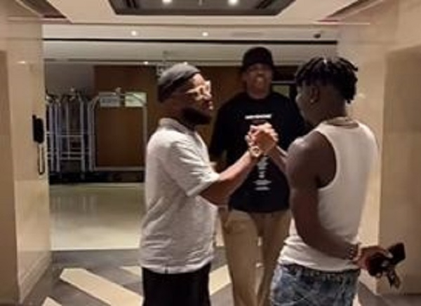 Stonebwoy in a handshake with Stonebwoy while Kanu looks on