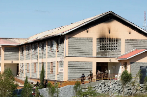 Security officers stand outside a burnt school dormitory in Gilgil