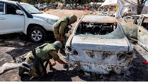 Soldiers search remains of a torched vehicle for forensic evidence in the Negev Desert