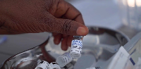 A healthcare worker holds up a vial of the Ervebo vaccine at an Ebola vaccination center