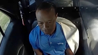 Woods can be seen hiccupping as he sits in the back of a police car
