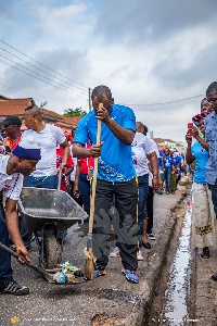 Dr Matthew Opoku Prempeh sweeping rubbish collected from a gutter