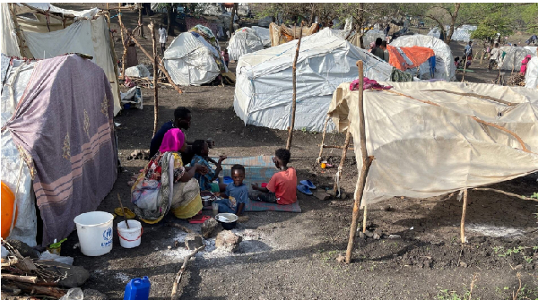 People sit by makeshift shelters near Awlala Camp, Amhara region, Ethiopia