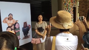 China's Ambassador to Ghana, Sun Baohong, poses with a cartoon criticizing China's role in Africa