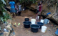 Obo residents scooping water from gutter.