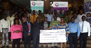 CEO of Opportunity International presenting a dummy cheque to a school proprietor