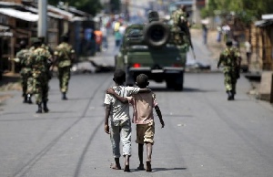 Boys Walk Behind Police Patrolling Streets Of Bujumbura, Burundi. Reuters