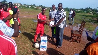 Hon Frank Okpenyen presenting the two boxes of water to the footballers
