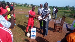 Hon Frank Okpenyen presenting the two boxes of water to the footballers