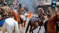 Police on horseback patrol a street in Nairobi on March 20, 2023 as protestors lit bonfires
