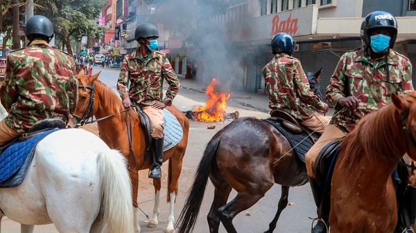 Police on horseback patrol a street in Nairobi on March 20, 2023 as protestors lit bonfires