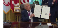 US President Donald Trump displays a signed executive order on what he calls 'gold card visas'