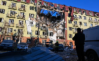 A rescue worker walks in front of a residential building that was heavily damaged after a Russian