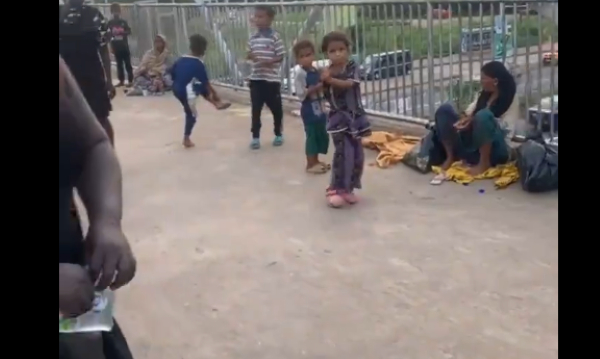 The beggar and her kids sitting on the footbridge