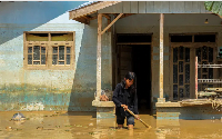 A girl walks through mud in front of her house in a flood-affected area in a province in  Indonesia