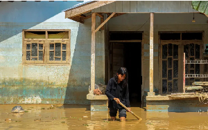 A girl walks through mud in front of her house in a flood-affected area in a province in  Indonesia